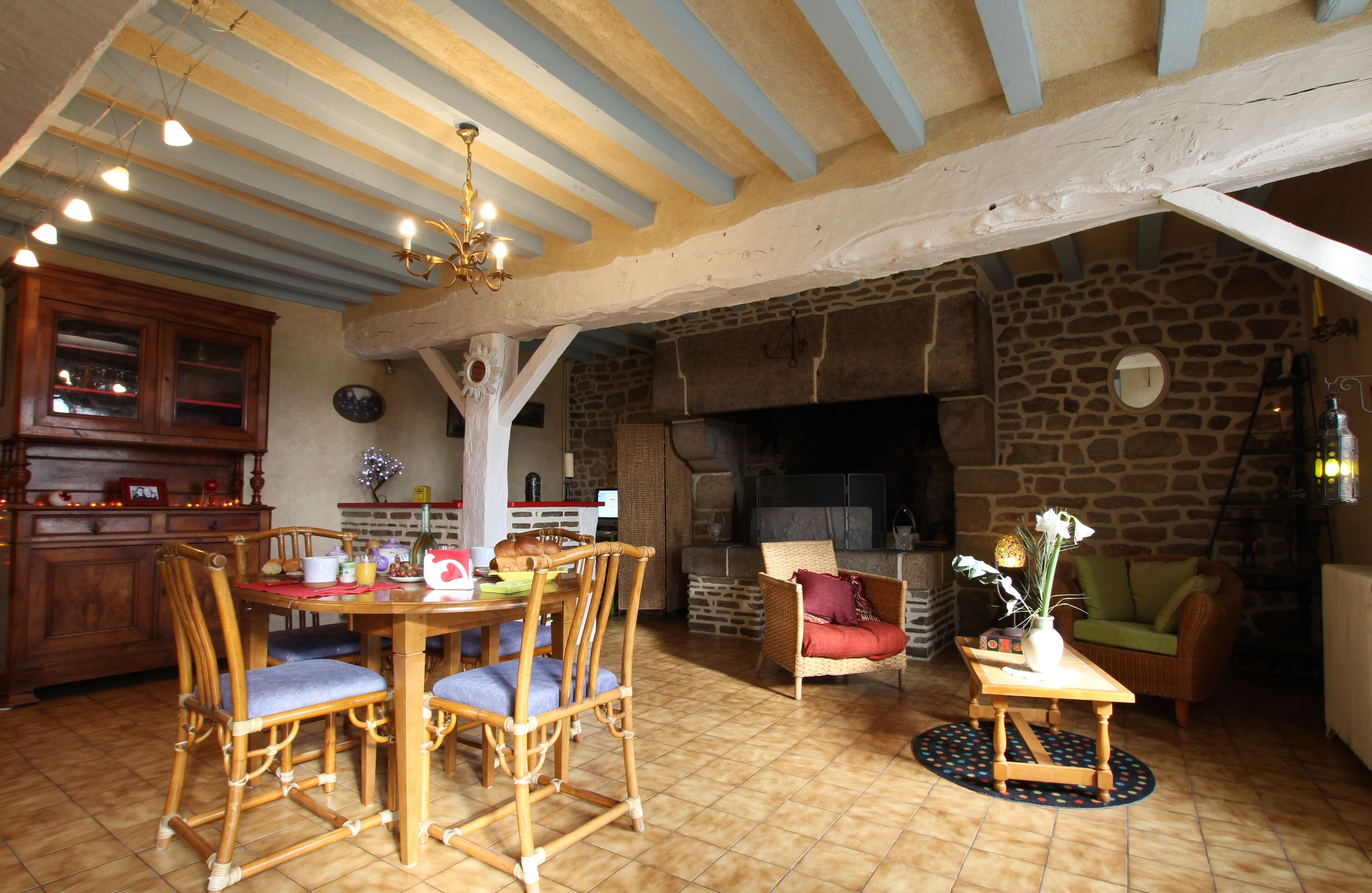 A rustic interior with a dining area, stone fireplace, and wooden furniture.