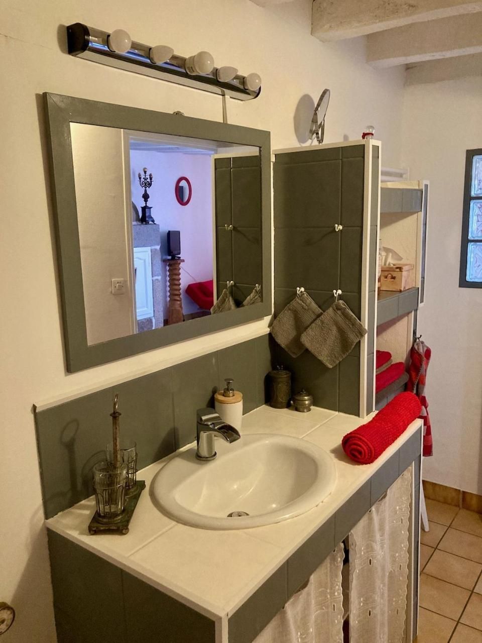 Un baño con un lavamanos blanco, un espejo y un perchero para toallas.