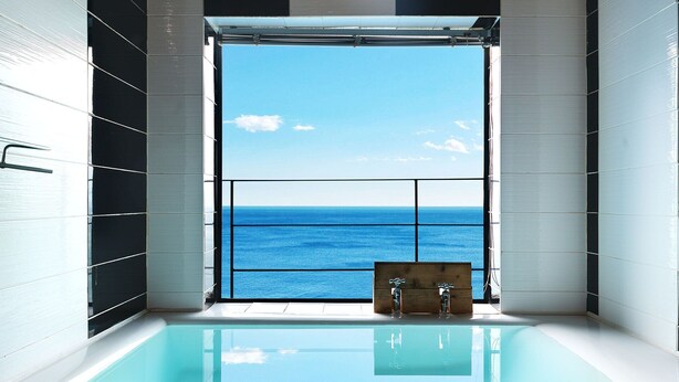 A modern bathroom with a large window offering a view of the sea.