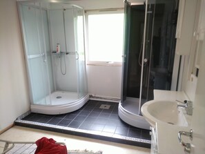 A bathroom with a glass-enclosed shower, a white sink, and a tiled floor. - Holandsvika Bomiljø (Vefsn)