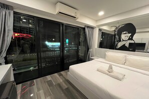 A hotel room with a large bed, a glass door leading to a balcony, and a wall-mounted air conditioner.