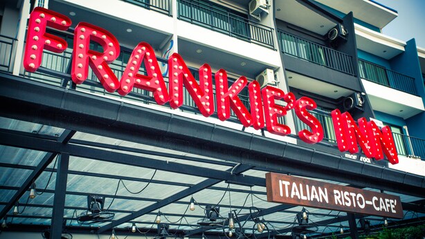 Un edificio con un letrero que dice "FRANKIES MAN" y otro letrero debajo que dice "ITALIAN RISTO-CAFE".