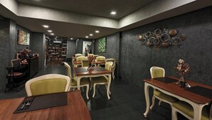 Ein moderner Essbereich mit einem langen Tisch und Stühlen, eine Barbereich mit einer Theke und Hockern sowie eine Wand mit runden Metalldekorationen.
