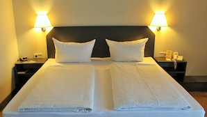 Una cama doble con dos almohadas, una mesita de noche con lámpara y un teléfono.