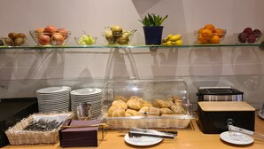 Disposición de buffet con varias frutas, pan y un tostador.
