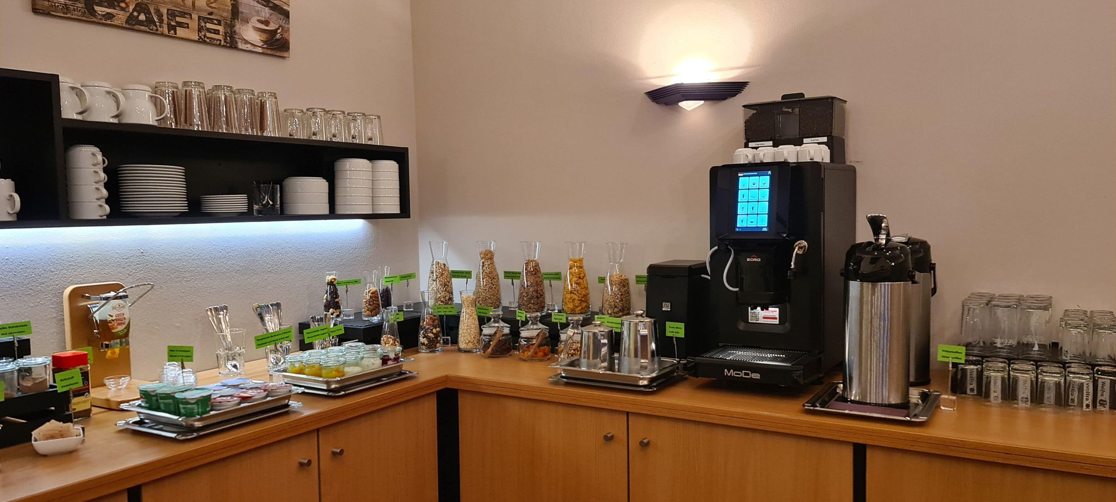 Ein reichhaltiges Buffet mit verschiedenen Speisen, einer Kaffeemaschine und Gläsern.