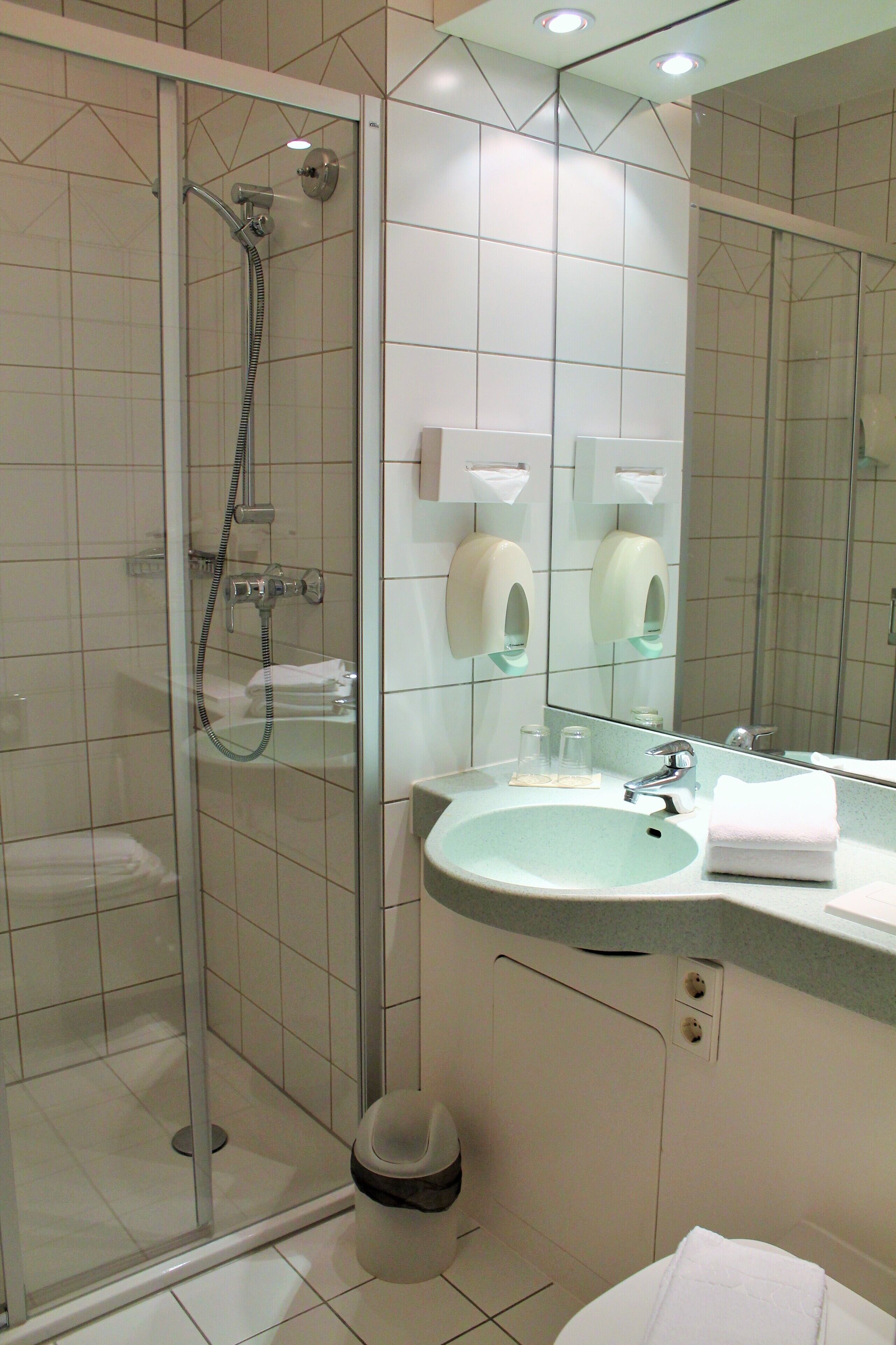 A bathroom with a glass-enclosed shower, a sink with a mirror, and a toilet.
