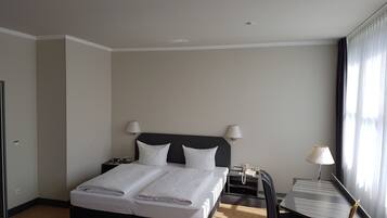 A hotel room with a bed, bedside tables, a desk, and a chair.