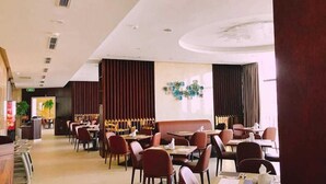 A modern restaurant with a clean, minimalist interior, featuring wooden paneling and a central seating area with tables and chairs. - Regalia Gold (Nha Trang)