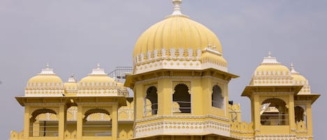 A large, yellow building with multiple domes and arched windows.
