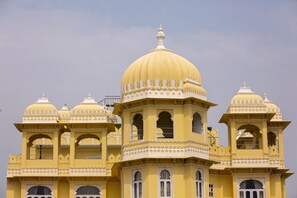 A large, yellow building with multiple domes and arched windows. - Bloom Boutique | Lake Pichola (Udaipur)
