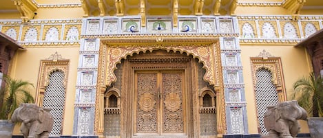 Fachada de edificio con tallas intrincadas y una puerta grande y ornamentada.