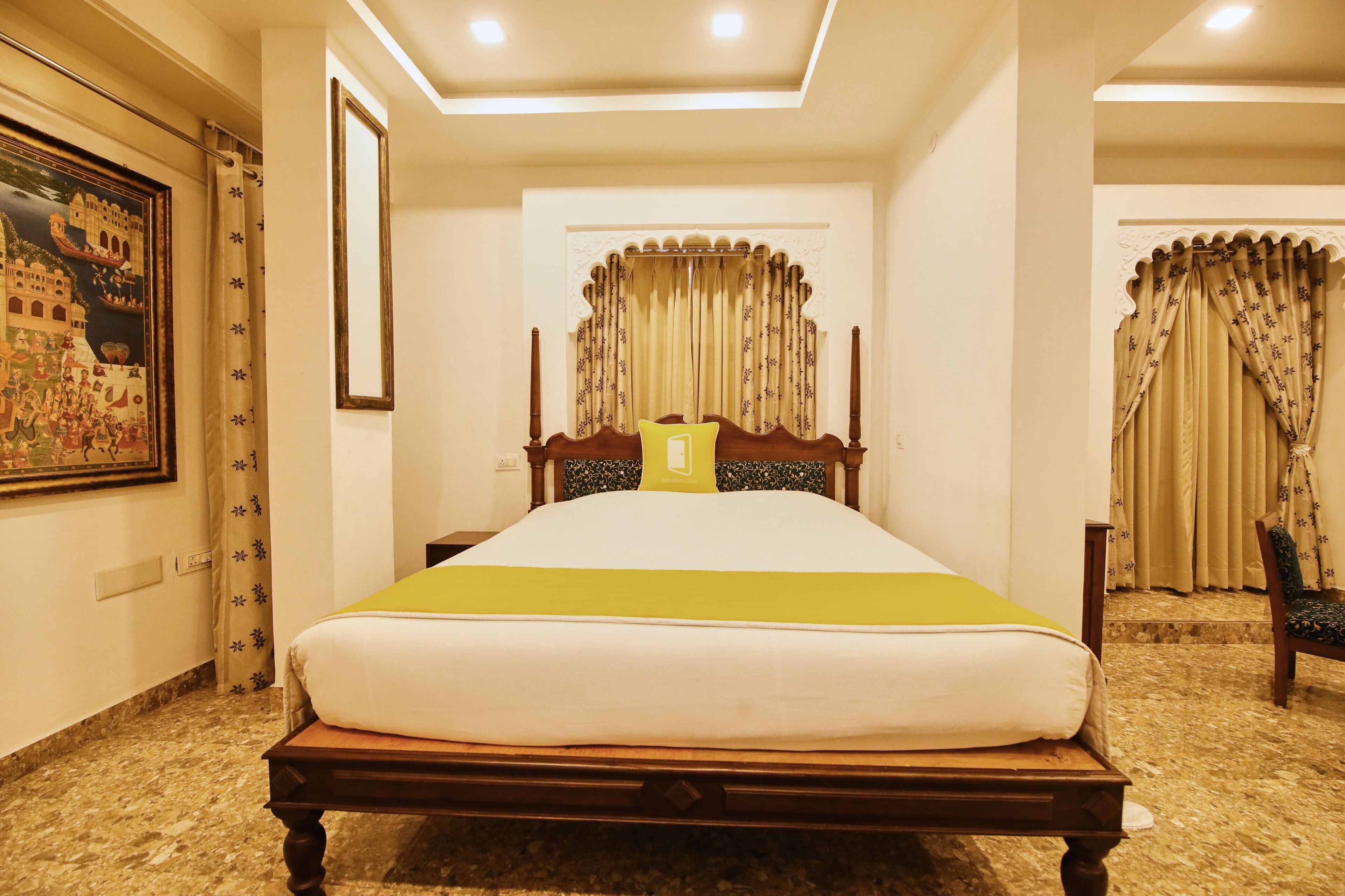 Habitación de hotel con una cama grande, cabecera con panel decorativo, un cuadro enmarcado en la pared y piso alfombrado.