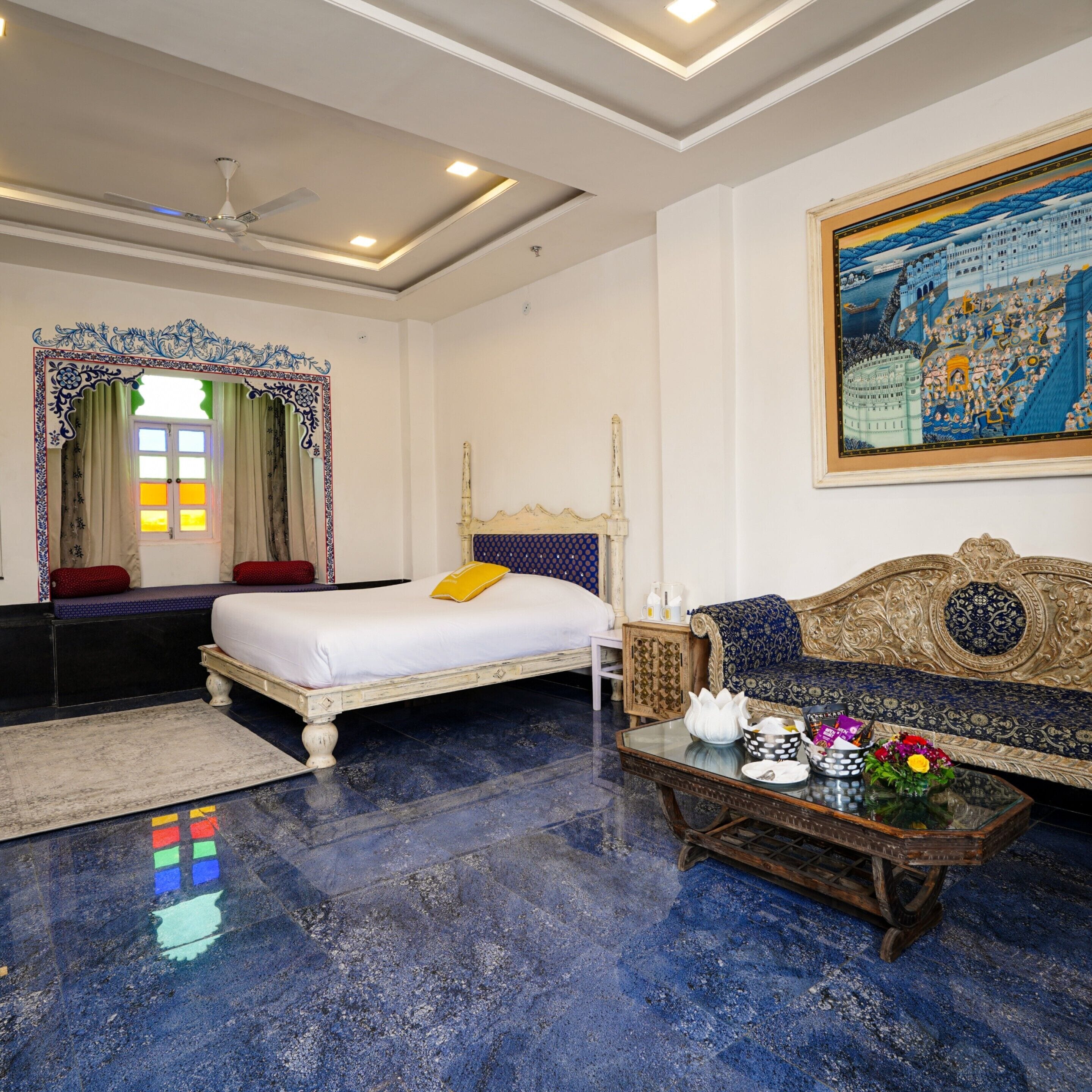 A room with a bed, a sofa, a coffee table, and a painting on the wall.
