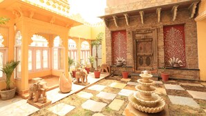A courtyard with a checkered floor, potted plants, and a decorative fountain.