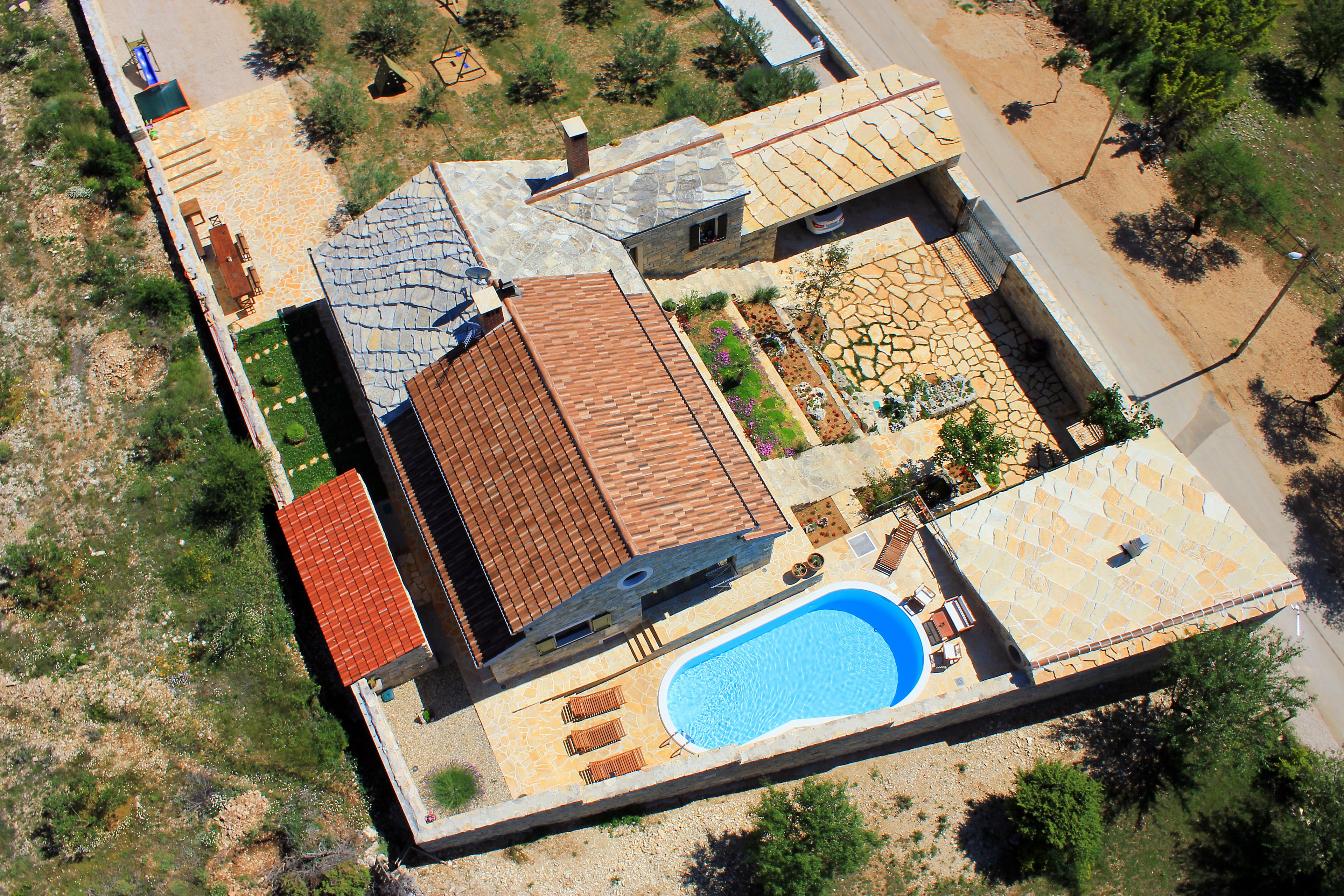 Vue aérienne d’une propriété résidentielle dotée d’une piscine, de plusieurs bâtiments et d’un jardin.