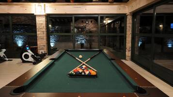 A pool table with a green felt surface, surrounded by a wooden frame.