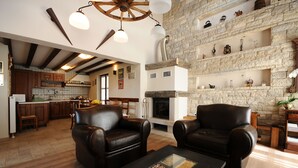 Amplia sala de estar con sofás de cuero, chimenea y pared de piedra.