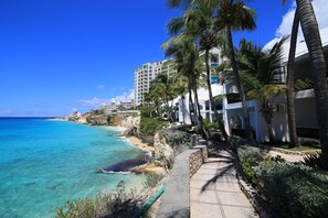 On the beach, beach umbrellas - Acadia Lovely Oceanfront, 1 to 3 Bedroom Condo is Located on the Cliffs of Cupecoy (Lowlands)
