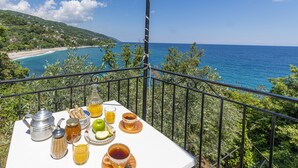 A balcony with a table set for breakfast overlooking a coastal view. - Katerina Fotopoulos Homes & Apartments (Zagora-Mouresi)