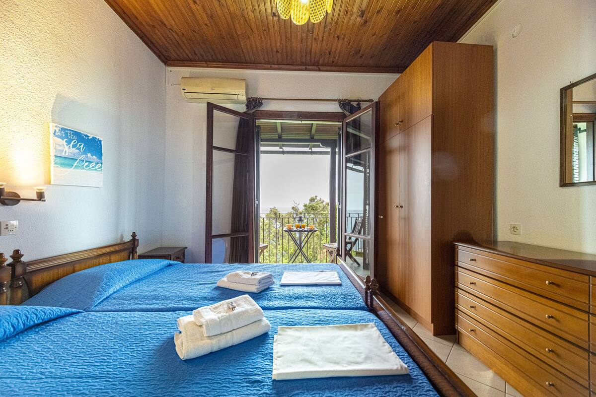 Una camera da letto con un letto, una cassettiera e un balcone con tavolo e sedie.