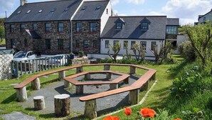 A courtyard with a circular seating area, surrounded by stone walls and wooden benches. - Corcreggan Mill (Dunfanaghy)