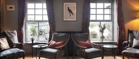 A room with two armchairs, a small table, and a large window with curtains.