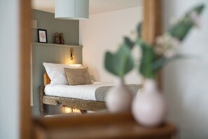A bedroom with a bed, pillows, a bedside table, and a mirror reflecting the room. - Corcreggan Mill (Dunfanaghy)