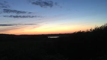 A sunset over a flat landscape with a body of water in the distance.