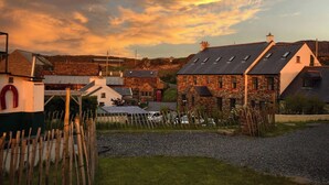 A rural village with stone houses, a gravel driveway, and a wooden fence. - Corcreggan Mill (Dunfanaghy)