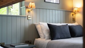 A bedroom with a bed, two wall-mounted lamps, and a window with a view of greenery. - Corcreggan Mill (Dunfanaghy)