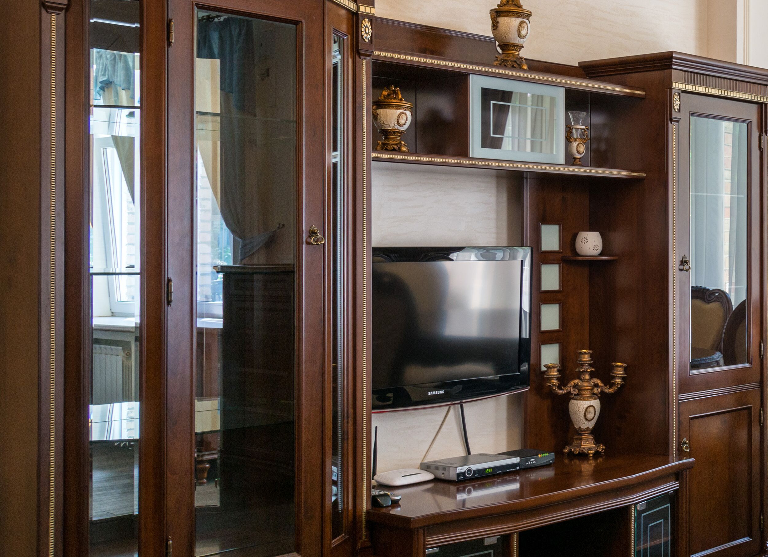 A wooden entertainment center with a flat-screen TV, a DVD player, and a decorative candelabra.
