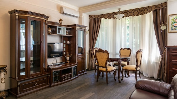 Ein Wohnzimmer mit einem Holzkasten, einem Fernseher und einem Essbereich mit Stühlen und einem Tisch.