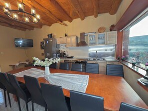 A modern kitchen with a wooden dining table, black chairs, and a view of the outdoors.