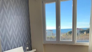 Une chambre à coucher avec un lit, une table de chevet et une fenêtre donnant sur la mer.