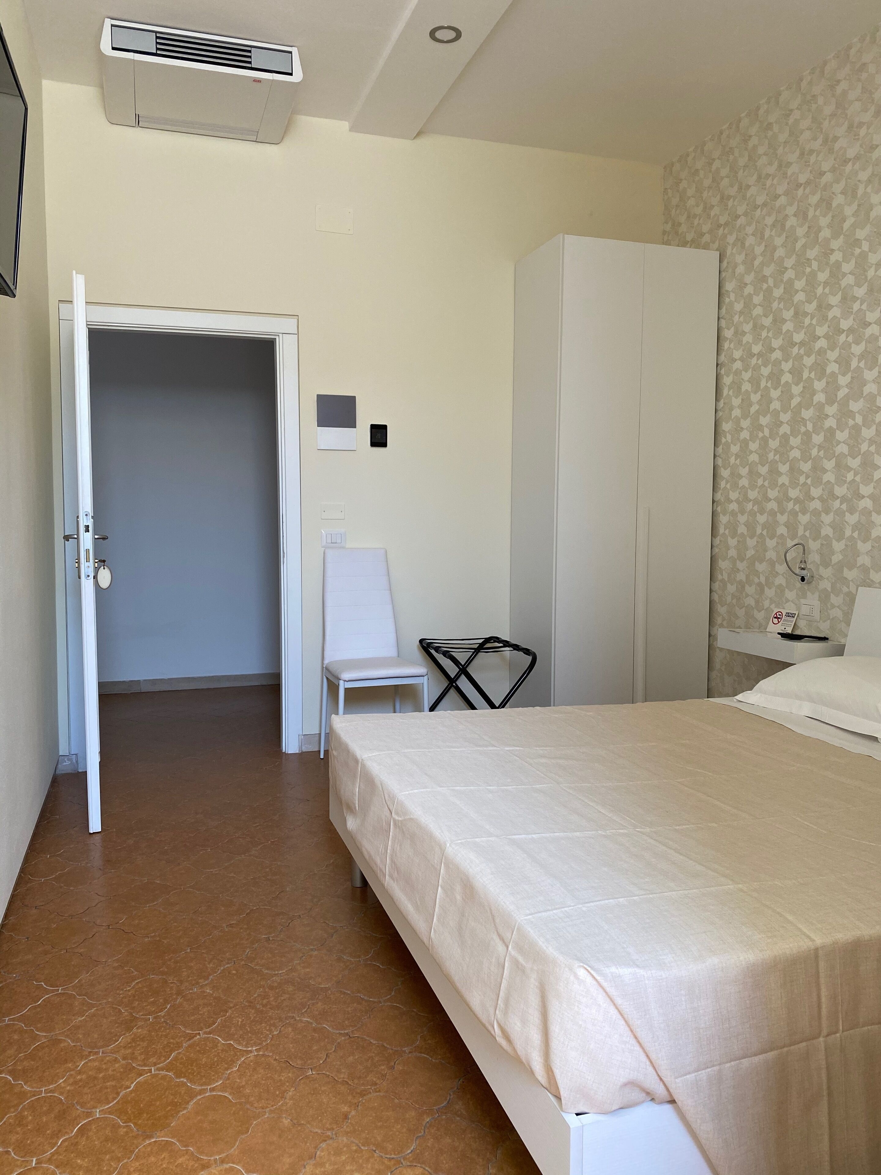 Une chambre d’hôtel comprenant un lit, une armoire, une chaise et un bureau avec un téléphone.