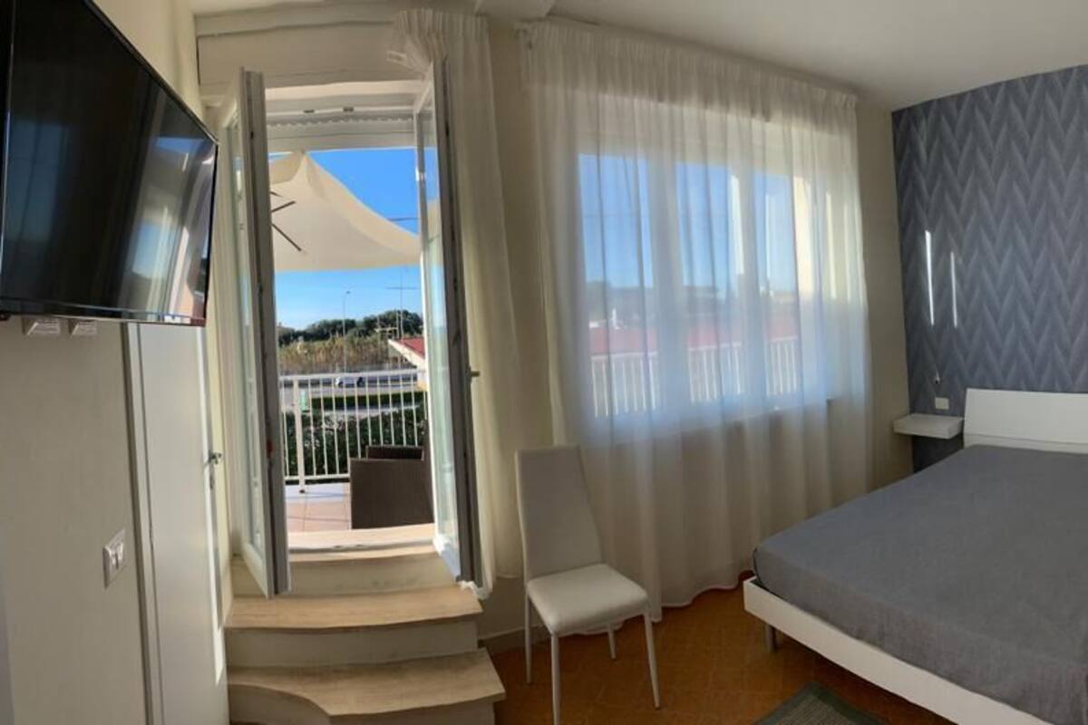 Ein Hotelzimmer mit Bett, Stuhl, Fernseher und einem Balkon mit Blick.