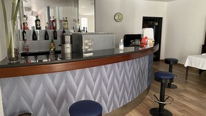 Un espace bar avec un comptoir, des tabourets et une horloge au mur.