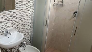 Un baño con ducha, lavamanos, lavaváteres y retrete.