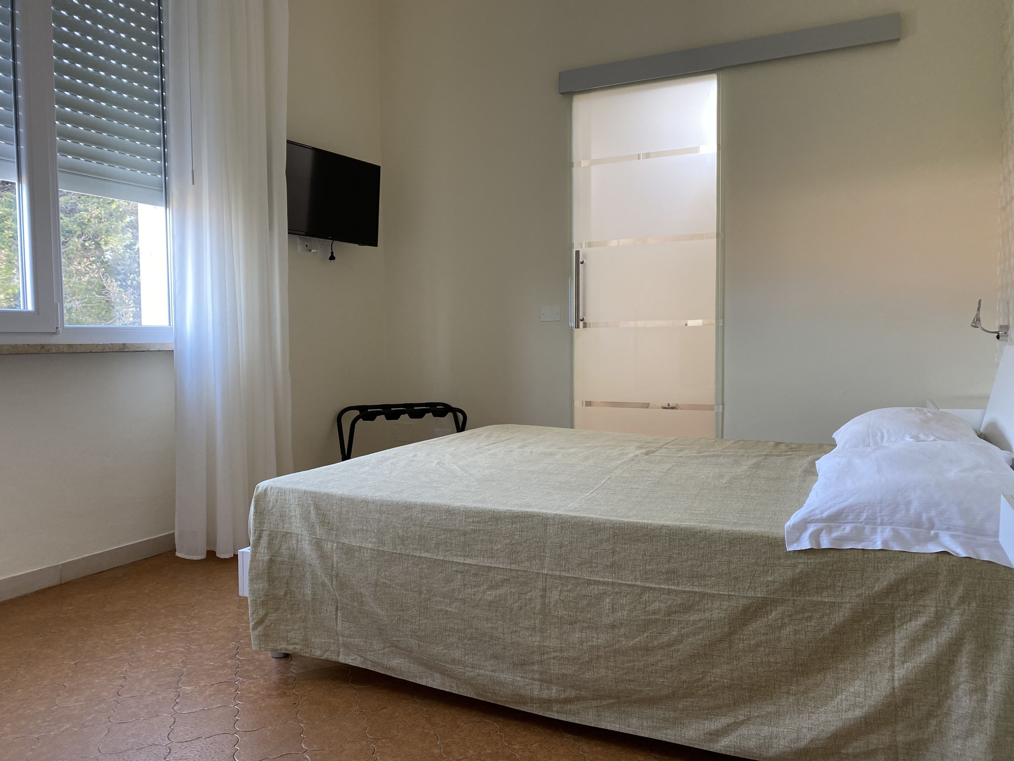 A bedroom with a bed, a TV mounted on the wall, and a sliding door closet.