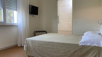 A bedroom with a bed, a TV mounted on the wall, and a sliding door closet.