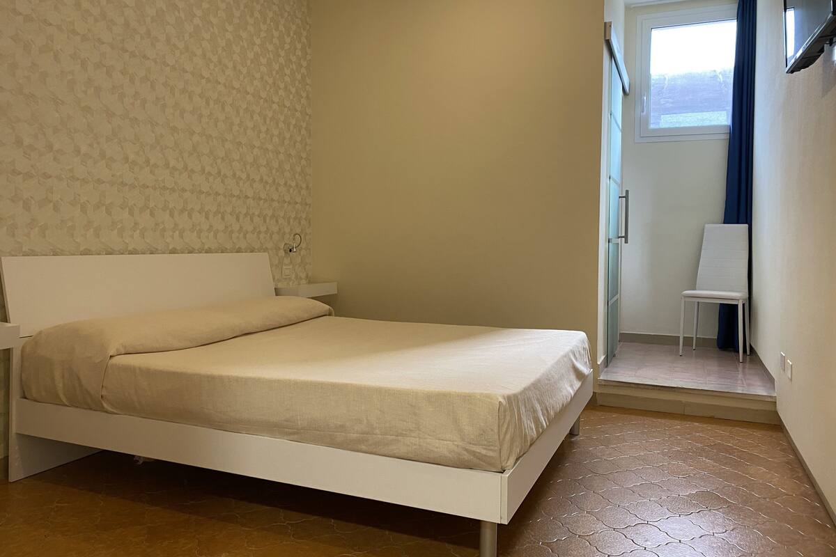 Ein Schlafzimmer mit einem Bett, einem Sessel und einem Fenster.