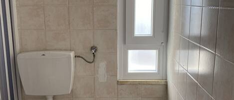 A small bathroom with a toilet, bidet, and a window.