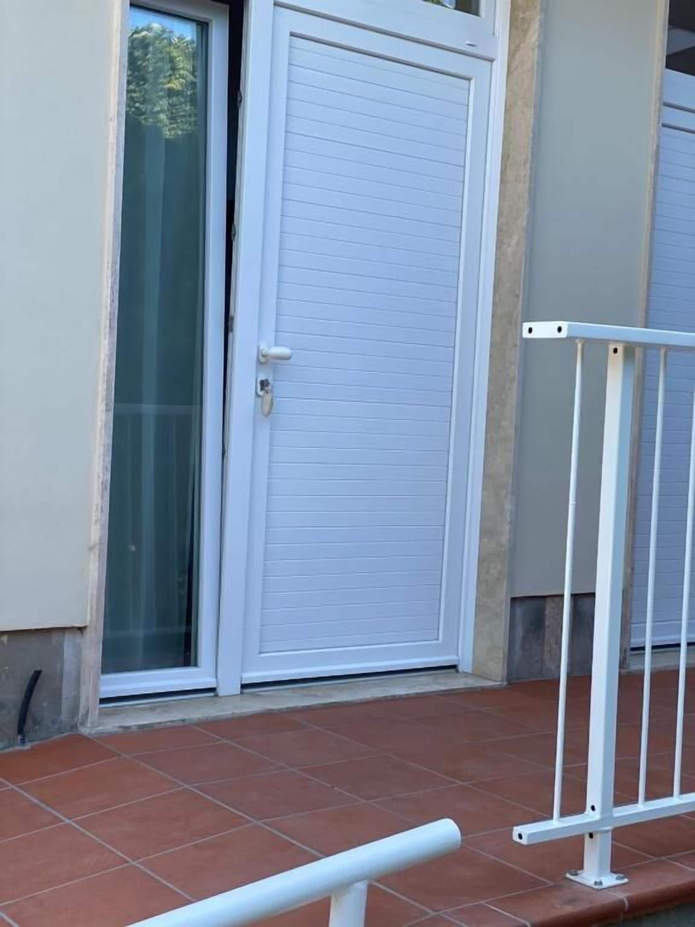 A closed white door with a keyhole and a glass door to the left.