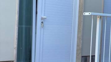 A closed white door with a keyhole and a glass door to the left.