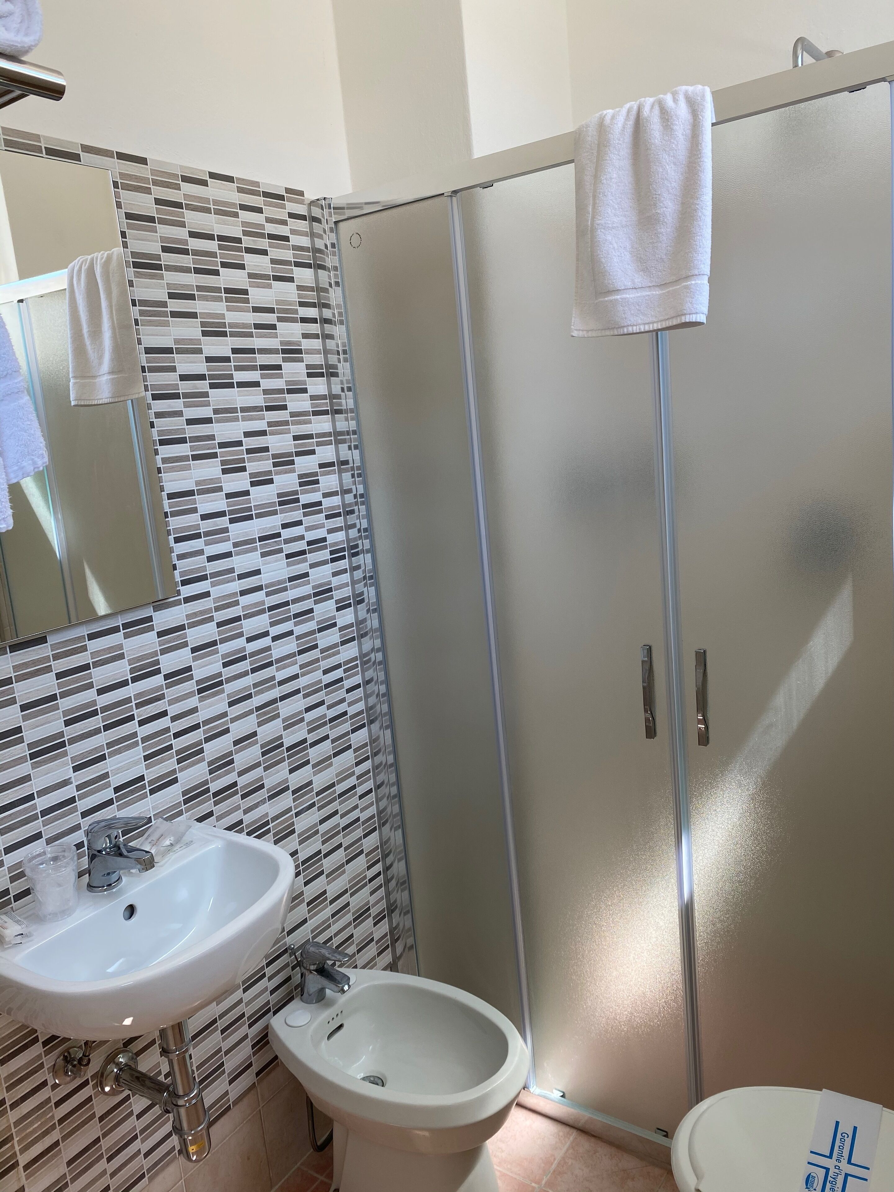 Un baño con lavamanos, bidé y cabina de ducha de vidrio.