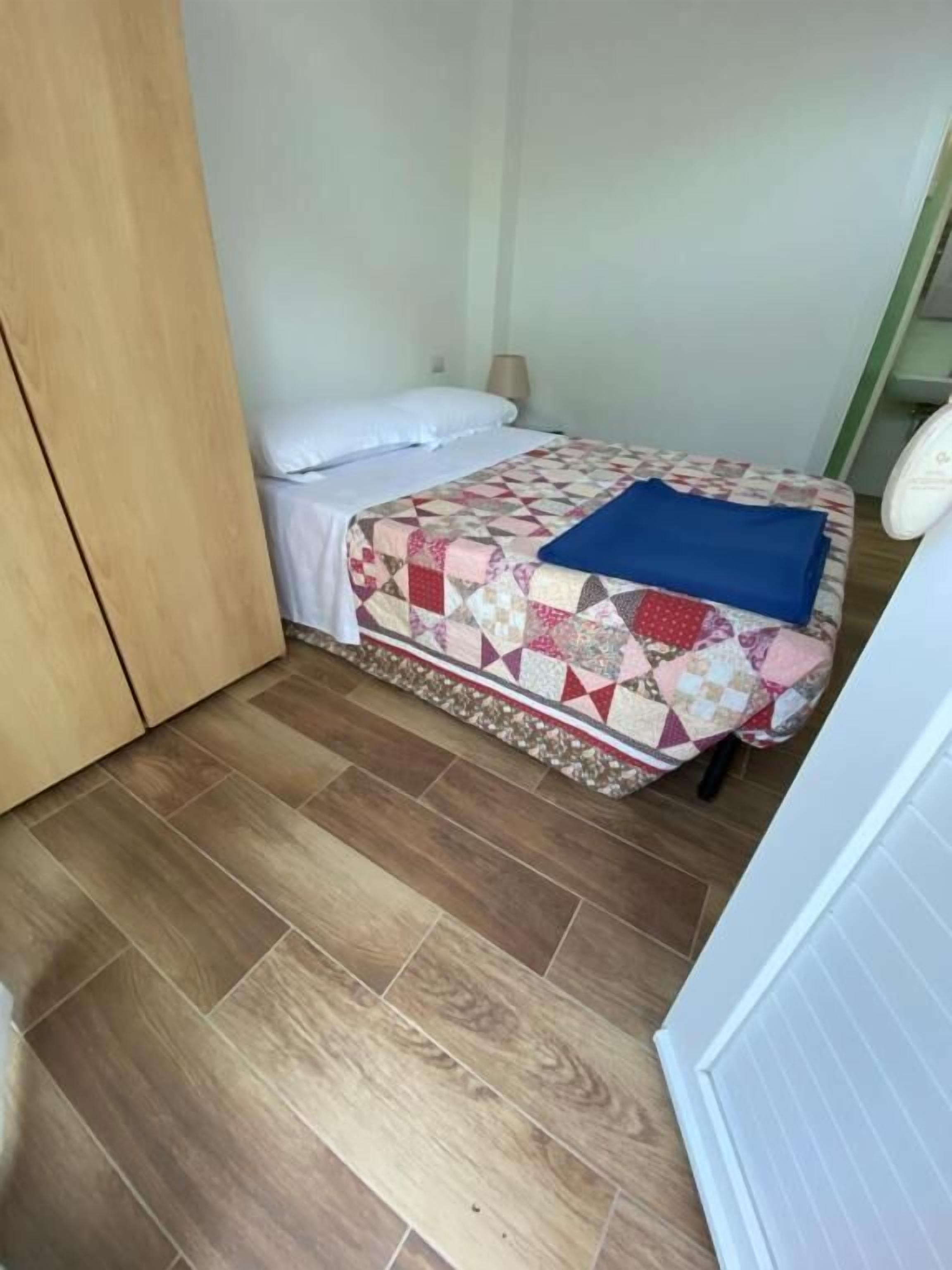 Ein Schlafzimmer mit einem Holzkasten, einem Bett mit Steppdecke und Holzboden.
