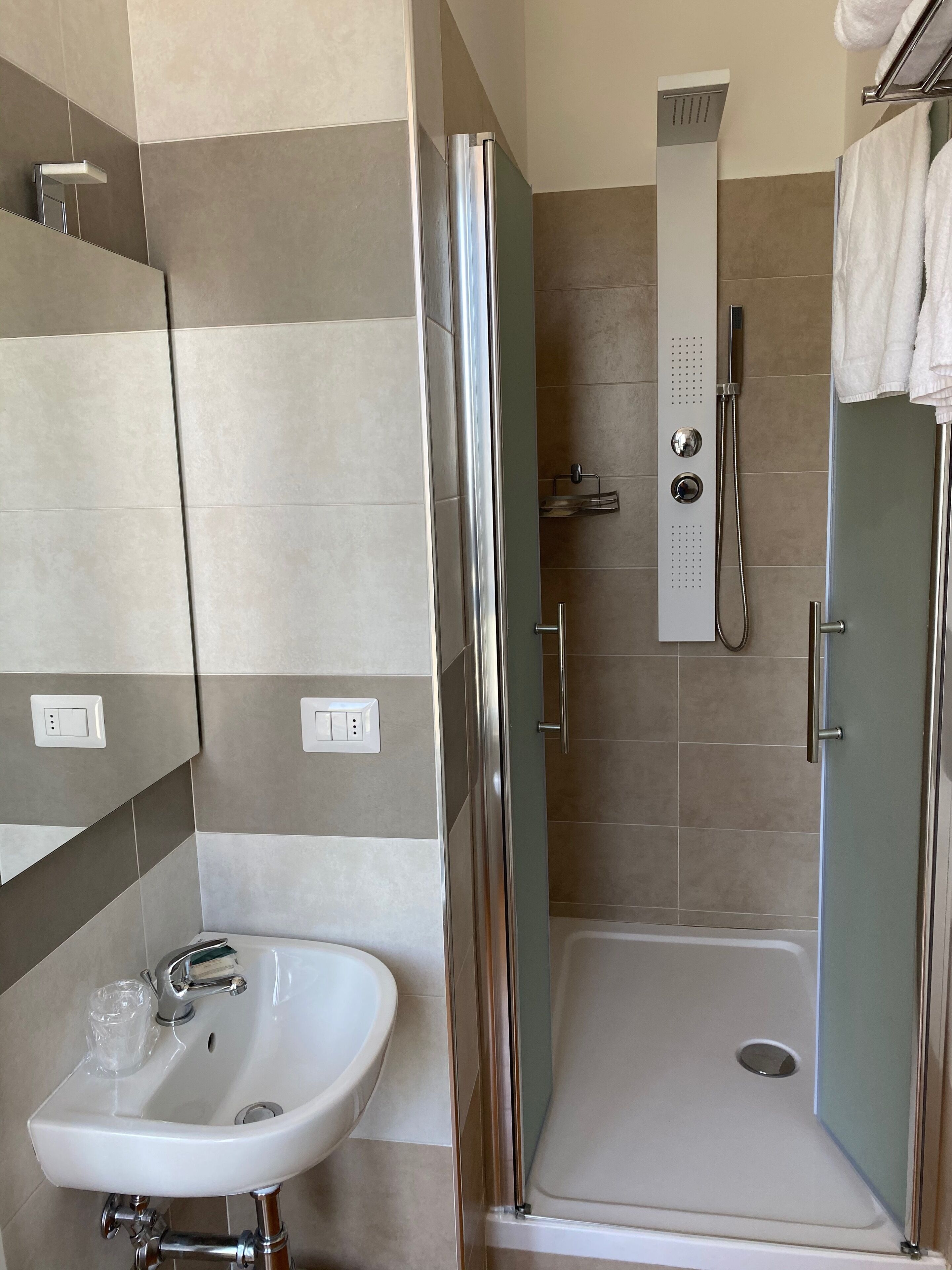 Un baño moderno con ducha acristalada, lavabo blanco y espejo.