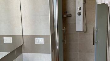 Une salle de bain moderne avec une douche à parois de verre, un lavabo blanc et un miroir.
