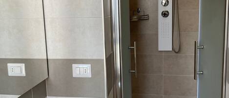 Un baño moderno con ducha acristalada, lavabo blanco y espejo.
